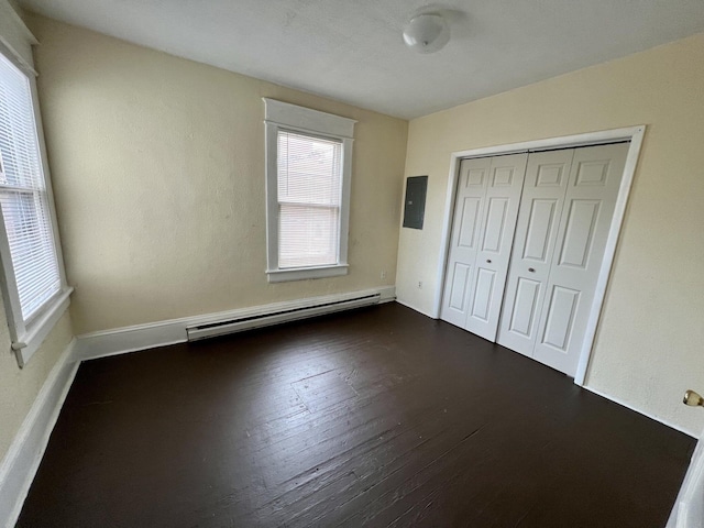 unfurnished bedroom featuring a baseboard radiator, a closet, hardwood / wood-style floors, and electric panel