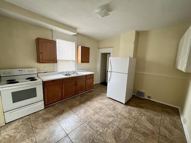 kitchen featuring sink, light tile patterned floors, and white appliances