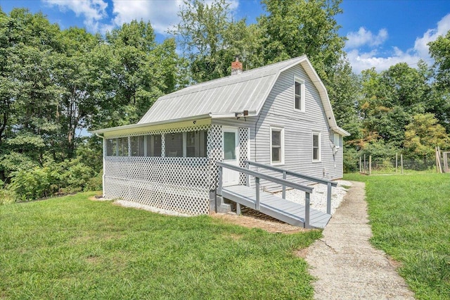 view of front of house featuring metal roof, a sunroom, a front yard, and a gambrel roof