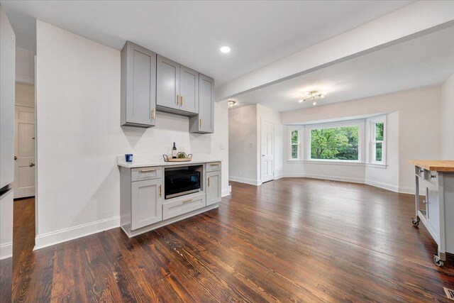 kitchen featuring gray cabinetry, dark hardwood / wood-style flooring, built in microwave, and butcher block countertops