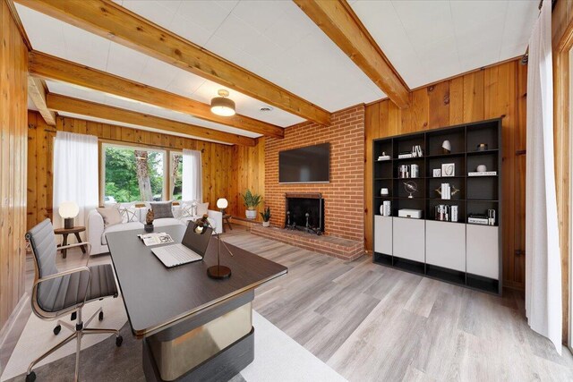 living room featuring wood walls, a fireplace, light wood-type flooring, beam ceiling, and brick wall