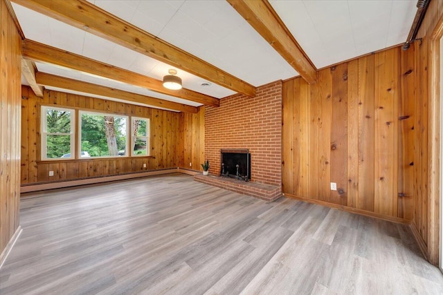 unfurnished living room featuring wood walls, a baseboard heating unit, light hardwood / wood-style floors, and a fireplace