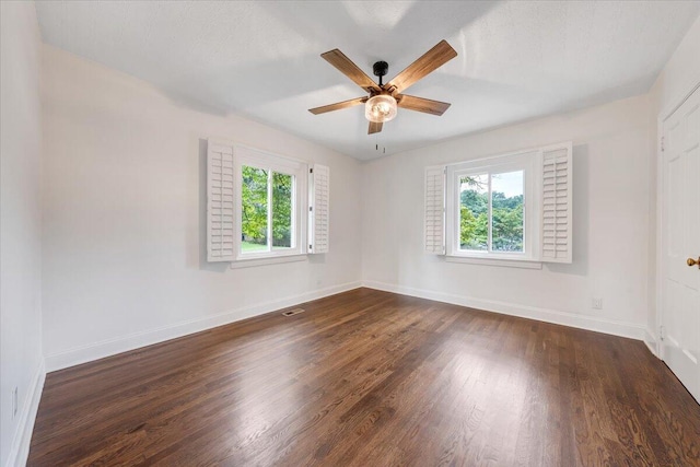 empty room with plenty of natural light, ceiling fan, and dark hardwood / wood-style flooring