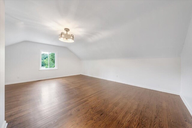 bonus room featuring vaulted ceiling and dark wood-type flooring