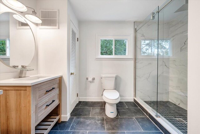 bathroom featuring tile patterned flooring, a shower with shower door, vanity, and toilet