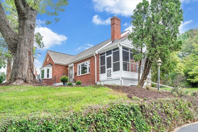 view of side of property featuring a sunroom and a yard