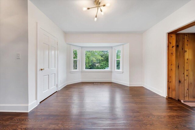 spare room featuring dark wood-type flooring and a baseboard radiator