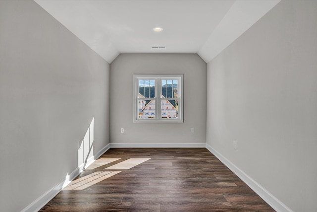 spare room with dark wood-type flooring and vaulted ceiling