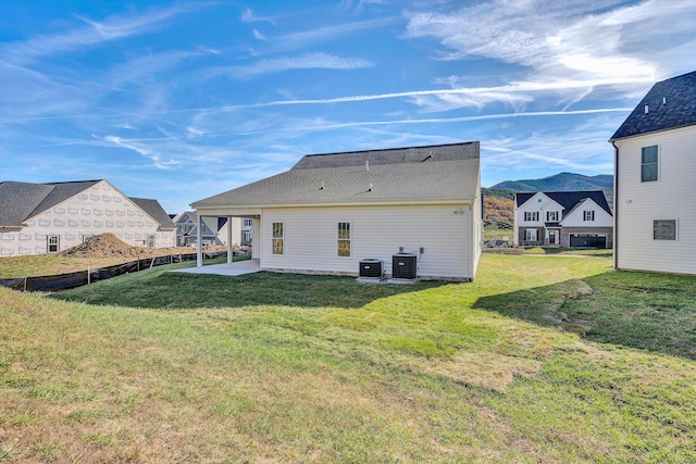 rear view of house with a lawn, cooling unit, and a patio