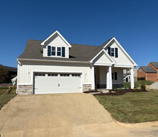 view of front of house with a porch, a garage, and a front lawn