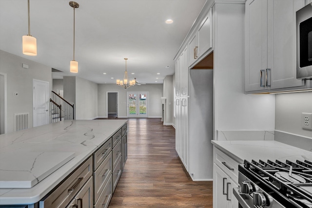 kitchen with light stone countertops, an inviting chandelier, dark hardwood / wood-style floors, pendant lighting, and white cabinets