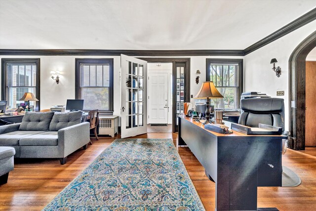 living room featuring radiator heating unit, ornamental molding, and hardwood / wood-style flooring