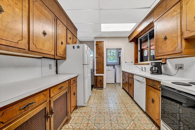 kitchen with separate washer and dryer, sink, a drop ceiling, light tile patterned floors, and white appliances