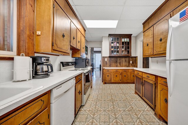 kitchen with a paneled ceiling, white appliances, and light tile patterned floors