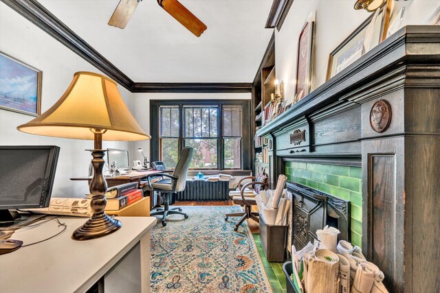 office area featuring hardwood / wood-style floors, crown molding, a tiled fireplace, and ceiling fan