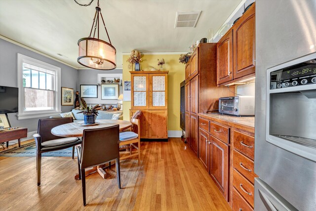 kitchen with light hardwood / wood-style flooring, crown molding, decorative light fixtures, and stainless steel fridge