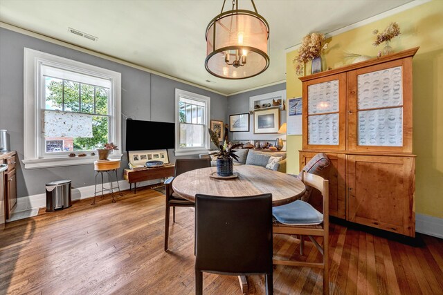 dining area featuring ornamental molding, an inviting chandelier, and hardwood / wood-style flooring