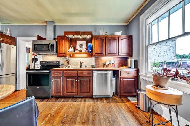 kitchen featuring light hardwood / wood-style flooring, tasteful backsplash, sink, crown molding, and stainless steel appliances