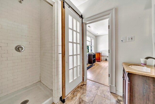 bathroom with tiled shower, wood-type flooring, and vanity