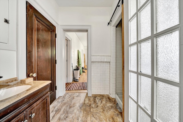 bathroom featuring tile patterned floors, a tile shower, and vanity