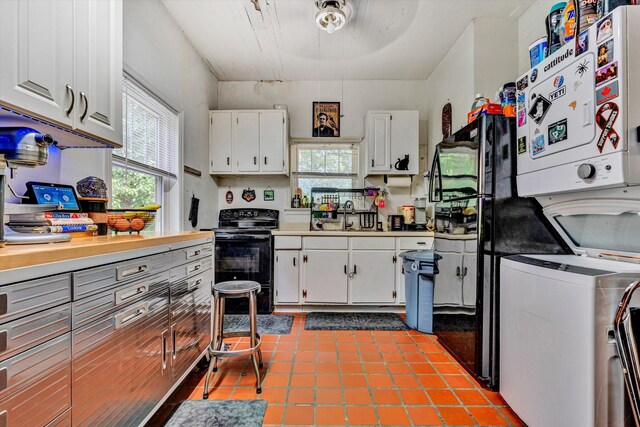 kitchen featuring white cabinets, sink, light tile patterned flooring, and black electric range