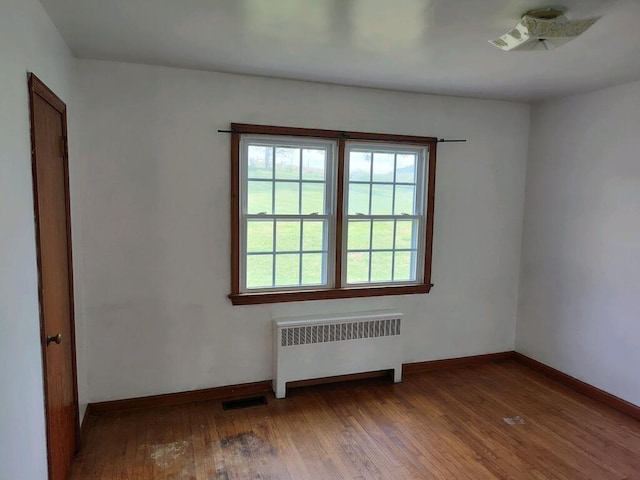 unfurnished room featuring hardwood / wood-style floors and radiator heating unit