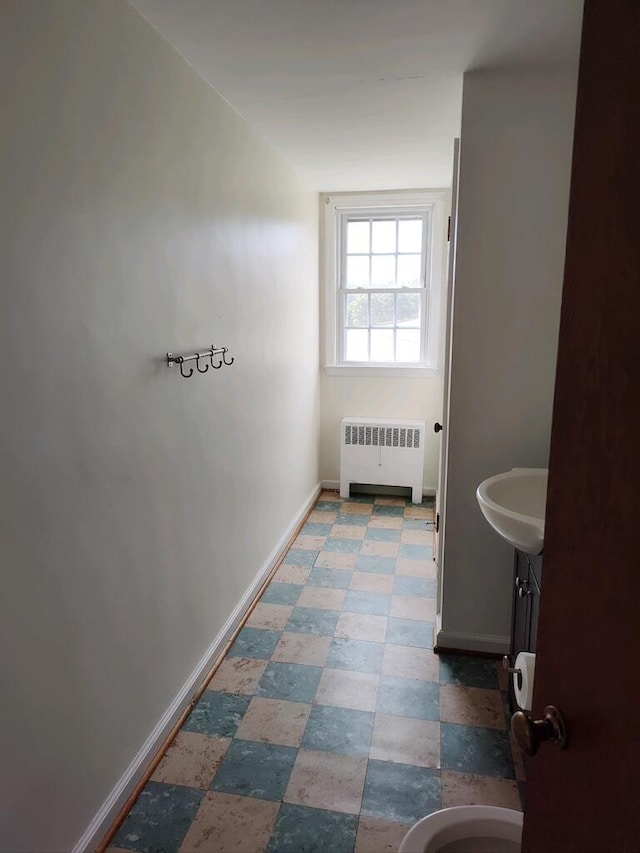 bathroom with radiator heating unit, sink, tile patterned flooring, and toilet