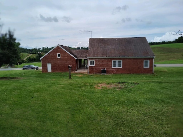 back of property featuring a garage and a lawn