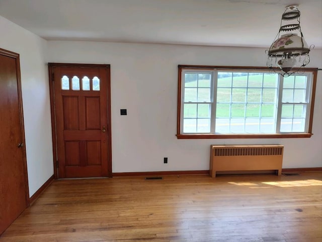 entrance foyer with plenty of natural light, radiator heating unit, an inviting chandelier, and light hardwood / wood-style flooring