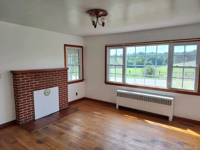 unfurnished living room with radiator heating unit and hardwood / wood-style floors