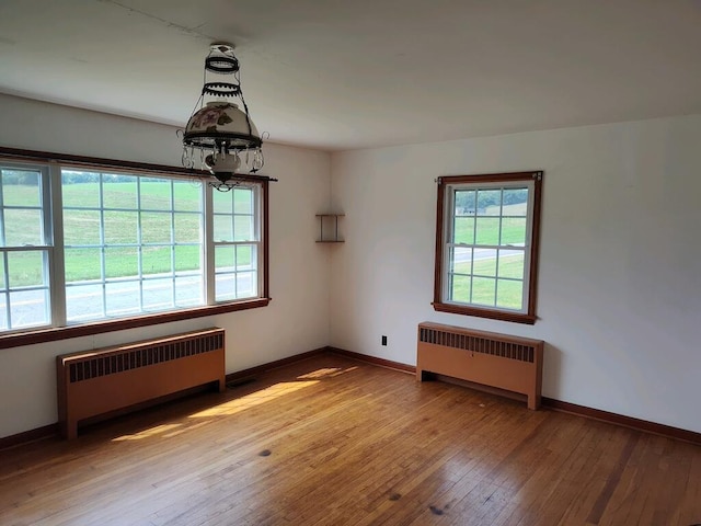 spare room featuring radiator heating unit and wood-type flooring