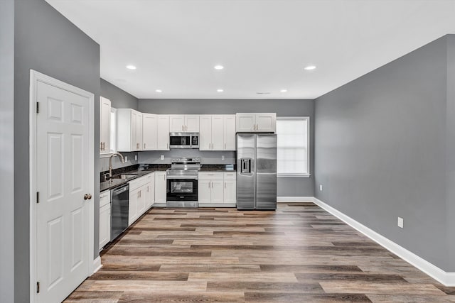 kitchen featuring sink, appliances with stainless steel finishes, white cabinets, and hardwood / wood-style floors