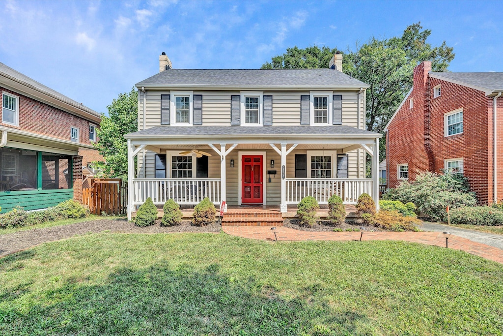 view of front of home featuring covered porch, a chimney, and a front lawn