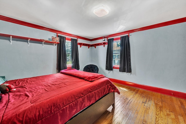 bedroom with ornamental molding and hardwood / wood-style flooring