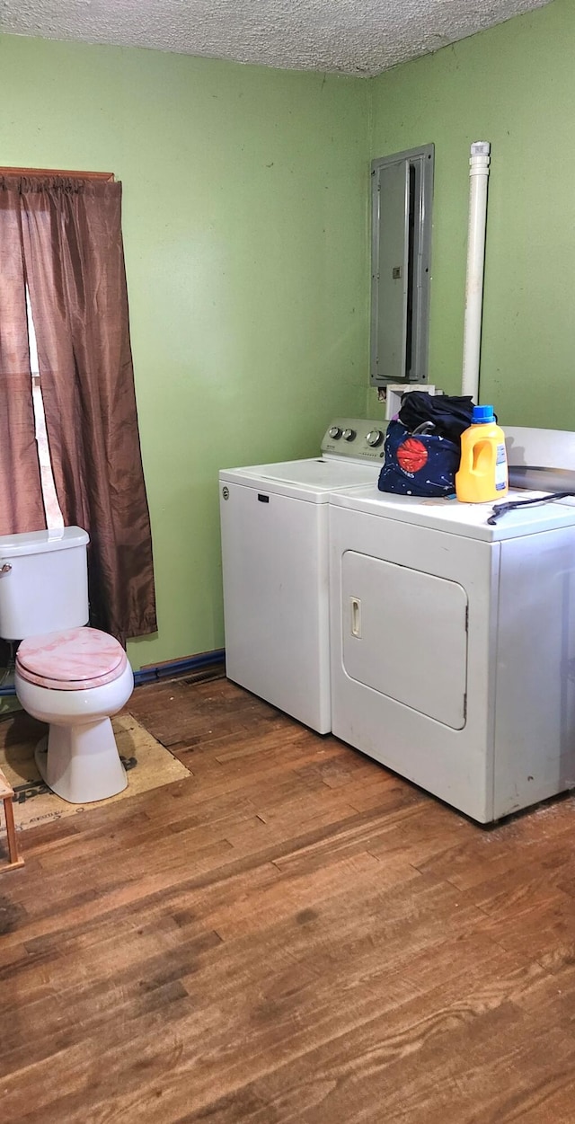 laundry room with a textured ceiling, electric panel, hardwood / wood-style floors, and independent washer and dryer