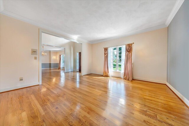 spare room with crown molding, a chandelier, and light hardwood / wood-style floors