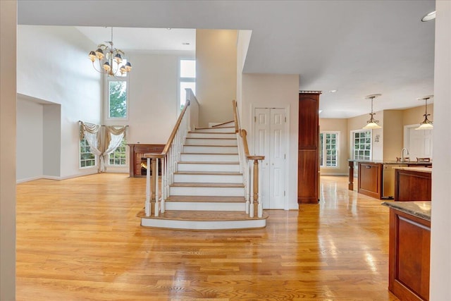 stairs with hardwood / wood-style flooring, sink, an inviting chandelier, and a towering ceiling