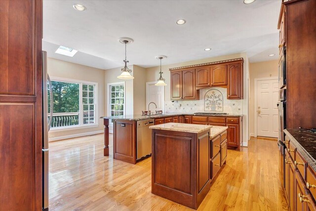 kitchen with sink, appliances with stainless steel finishes, a center island, decorative light fixtures, and kitchen peninsula