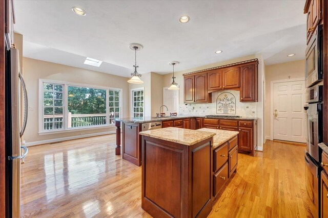 kitchen featuring a kitchen island, pendant lighting, sink, kitchen peninsula, and stainless steel appliances