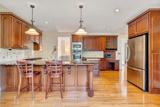 kitchen featuring stainless steel appliances, a breakfast bar area, and dark stone counters