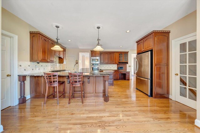 kitchen with stone counters, appliances with stainless steel finishes, pendant lighting, a kitchen breakfast bar, and kitchen peninsula