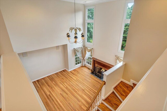 stairs with hardwood / wood-style flooring, a brick fireplace, and a notable chandelier