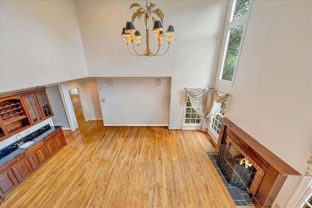 living room with light hardwood / wood-style floors, a chandelier, and a high ceiling