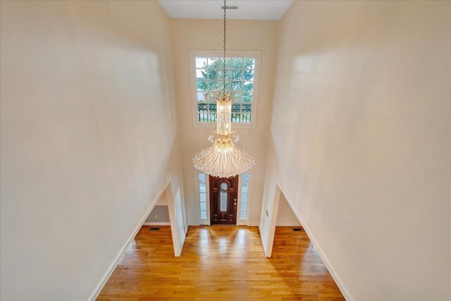 entrance foyer featuring light wood-type flooring, an inviting chandelier, and a towering ceiling