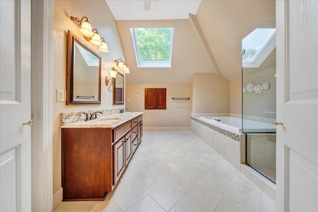 bathroom with a relaxing tiled tub, vanity, tile patterned floors, and vaulted ceiling with skylight