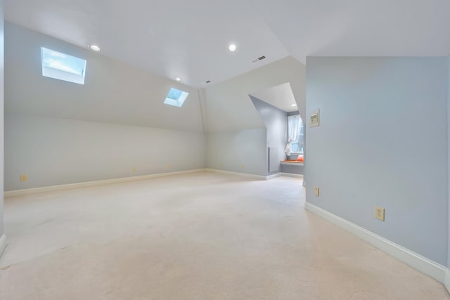 additional living space with plenty of natural light, light colored carpet, and vaulted ceiling with skylight