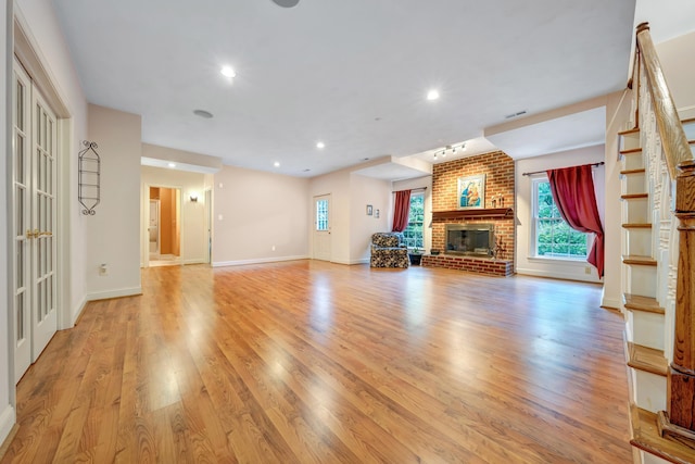 unfurnished living room with a brick fireplace and light hardwood / wood-style floors