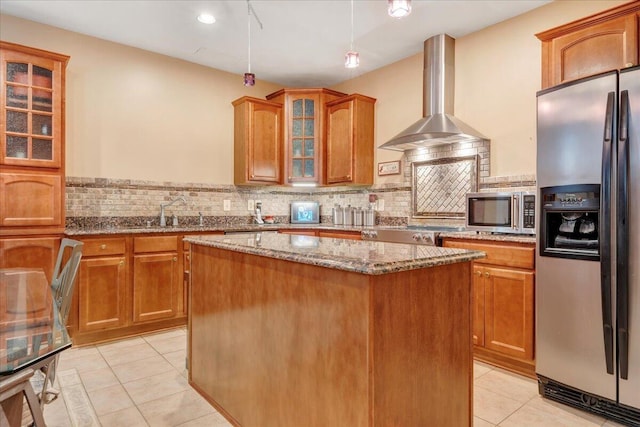 kitchen with appliances with stainless steel finishes, a center island, light stone counters, decorative backsplash, and wall chimney exhaust hood