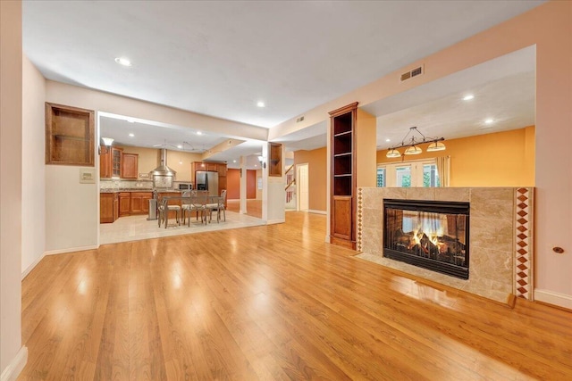 unfurnished living room featuring a tile fireplace and light wood-type flooring