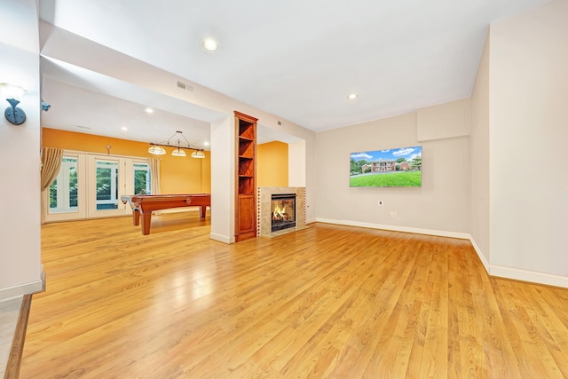 unfurnished living room featuring pool table, built in features, a fireplace, and light hardwood / wood-style flooring